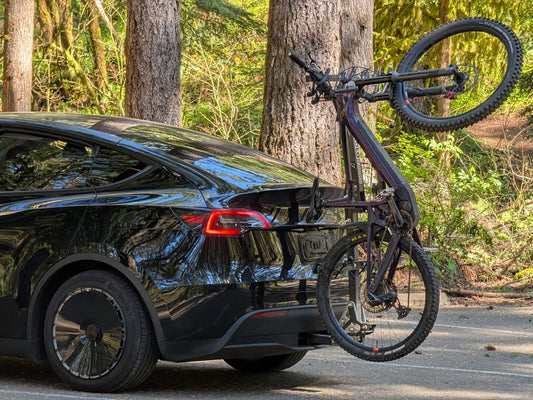 A black electric vehicle with a foldable bike rack attached to the rear, showcasing the rack's ability to carry bikes while maintaining a sleek profile.